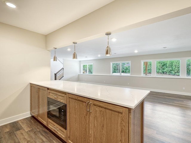 kitchen with light stone countertops, dark hardwood / wood-style flooring, black microwave, and hanging light fixtures