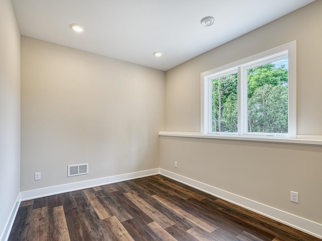 empty room featuring visible vents, dark wood-style flooring, baseboards, and recessed lighting