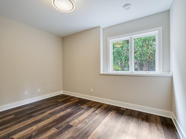 unfurnished room featuring baseboards and dark wood-style floors