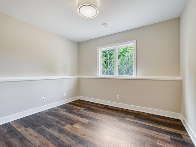 empty room with dark wood-style flooring and baseboards