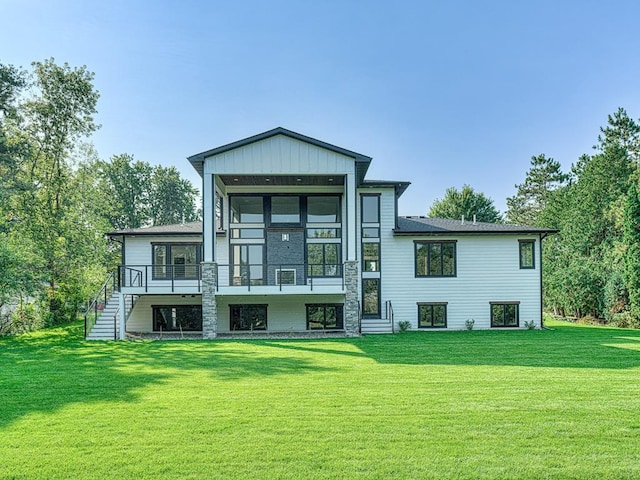 rear view of property featuring a wooden deck, a lawn, and stairs