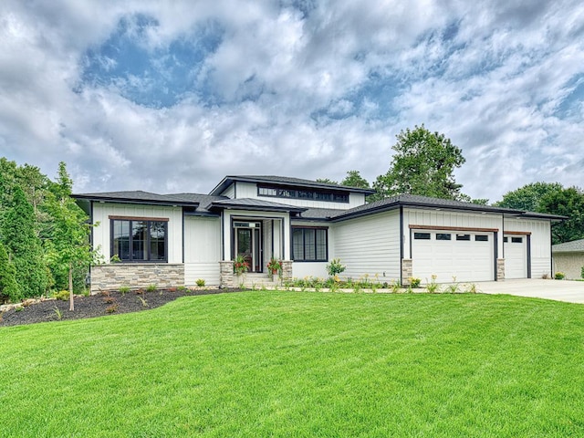 prairie-style house featuring an attached garage, a front lawn, stone siding, and driveway