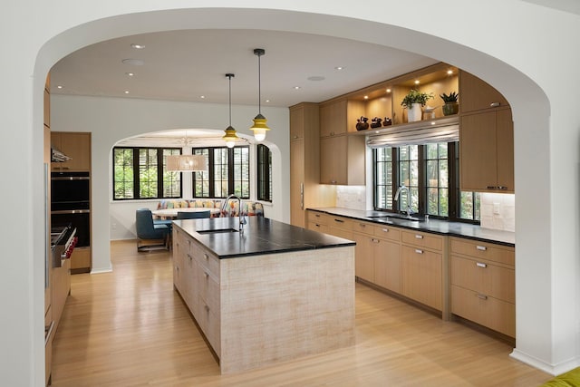 kitchen with plenty of natural light, an island with sink, and tasteful backsplash