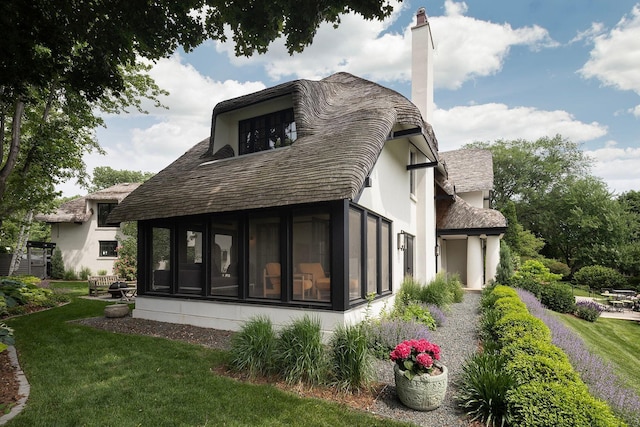 back of property with a sunroom and a lawn