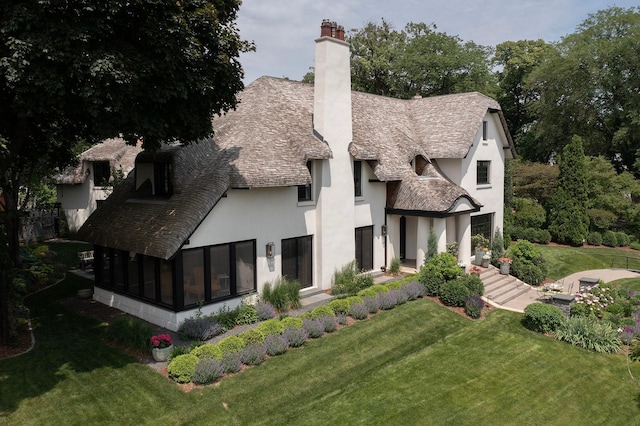 back of property with a sunroom and a lawn