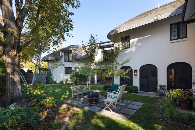 rear view of property featuring a yard, an outdoor fire pit, and a patio