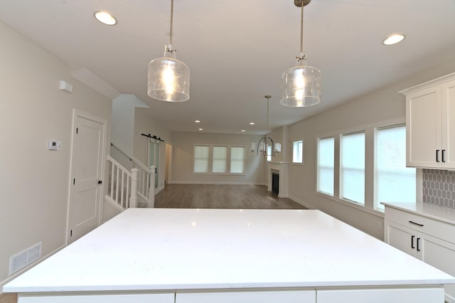 kitchen with white cabinets, decorative backsplash, a kitchen island, and hanging light fixtures