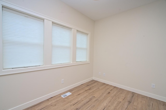 spare room featuring light wood-style floors, baseboards, and visible vents