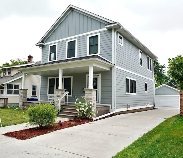 view of front of home with a detached garage, a porch, board and batten siding, and an outbuilding