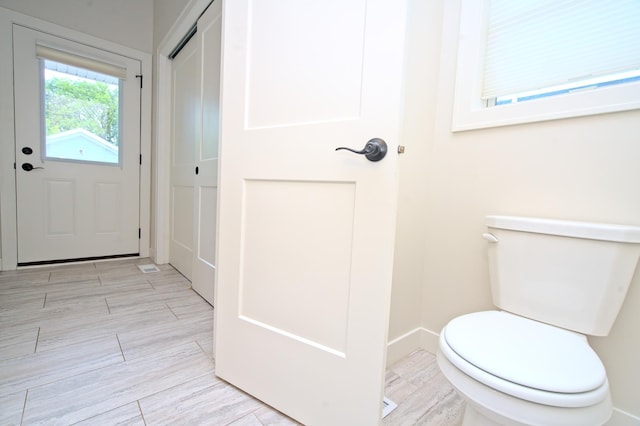 bathroom with toilet, baseboards, and wood finish floors