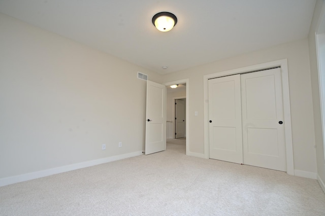 unfurnished bedroom featuring light carpet, a closet, visible vents, and baseboards