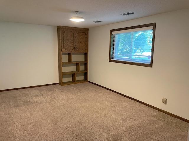 spare room featuring a textured ceiling and light colored carpet