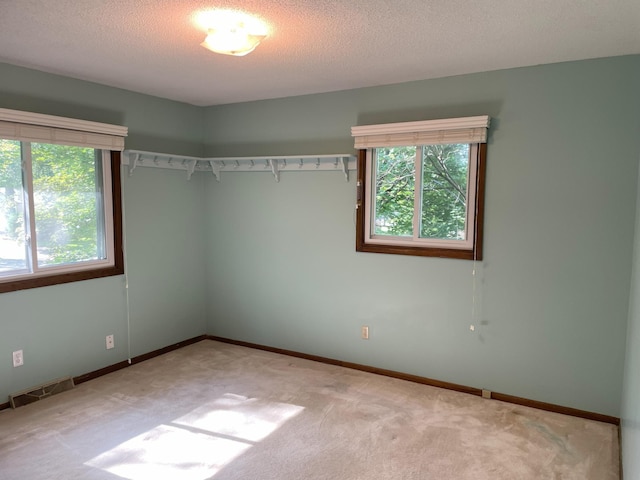 carpeted spare room featuring a textured ceiling