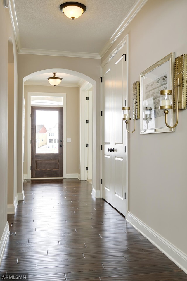 foyer with a textured ceiling, dark wood-type flooring, and ornamental molding