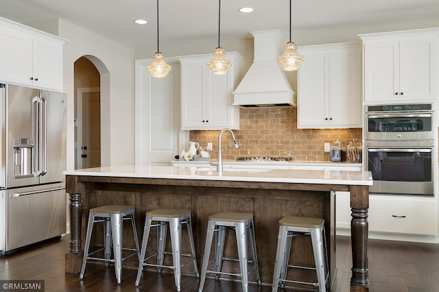 kitchen featuring stainless steel appliances, premium range hood, dark hardwood / wood-style flooring, and tasteful backsplash