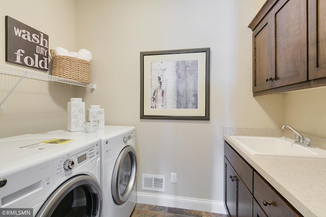 clothes washing area featuring cabinets, washing machine and dryer, and sink