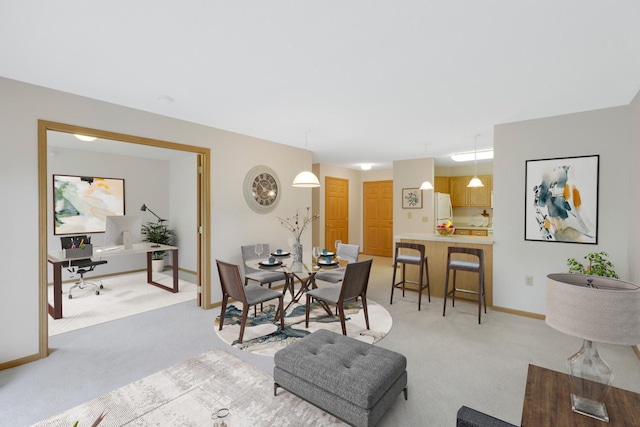 dining space featuring light carpet and baseboards