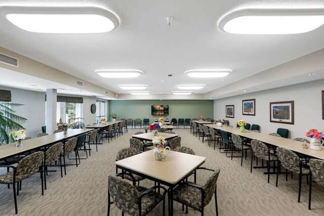 dining room with light carpet and a textured ceiling