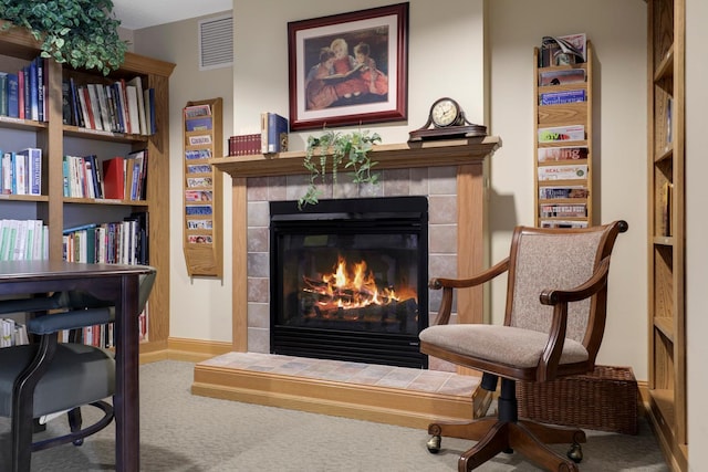 sitting room featuring a tiled fireplace and carpet flooring