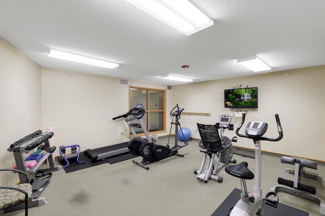 workout room featuring a textured ceiling and carpet flooring