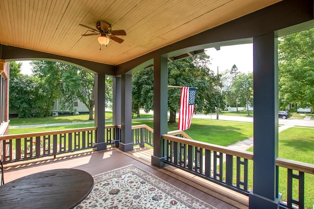 deck with ceiling fan, covered porch, and a yard