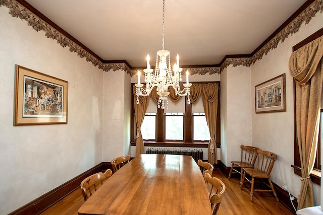 dining room with ornamental molding, wood-type flooring, a chandelier, and radiator