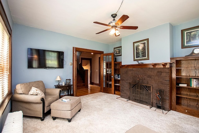 living room featuring light wood-type flooring, a wealth of natural light, ceiling fan, and a brick fireplace