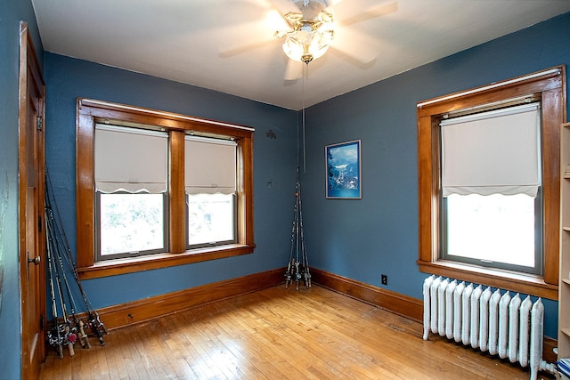 empty room with light hardwood / wood-style floors, radiator, and ceiling fan