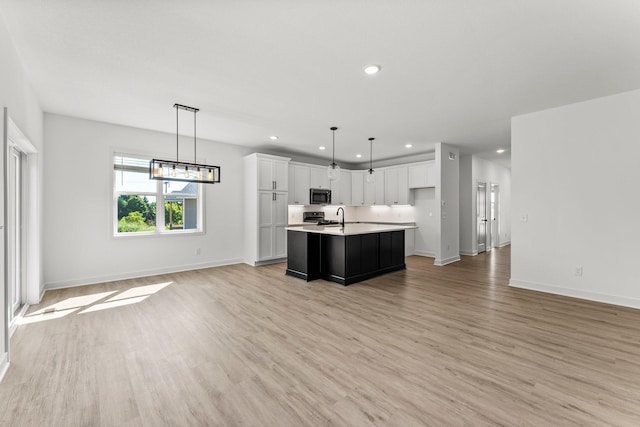 kitchen featuring a kitchen island with sink, light wood-type flooring, and white cabinetry