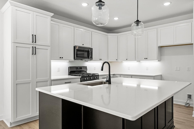 kitchen with white cabinets, an island with sink, and black range with gas stovetop