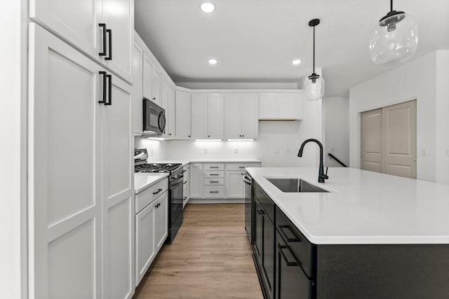 kitchen with hanging light fixtures, white cabinetry, sink, and stainless steel appliances