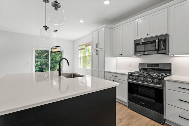 kitchen with stainless steel appliances, white cabinets, hanging light fixtures, and sink