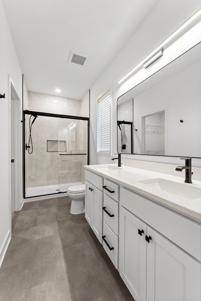 bathroom featuring vanity, toilet, and a shower with door