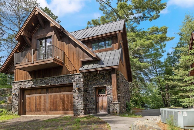 view of front of property featuring central AC unit, a balcony, and a garage