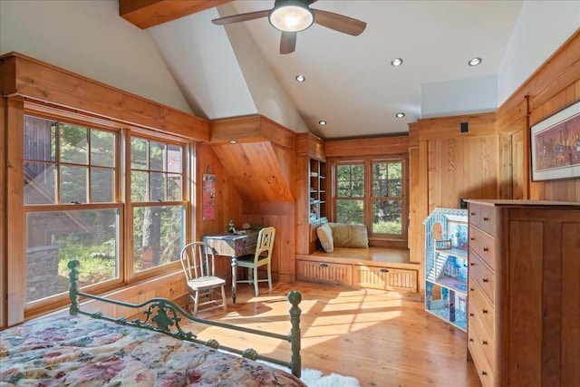 bedroom featuring multiple windows, light hardwood / wood-style flooring, lofted ceiling, and wooden walls