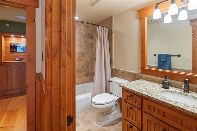 full bathroom featuring toilet, vanity, tile walls, and shower / bath combo