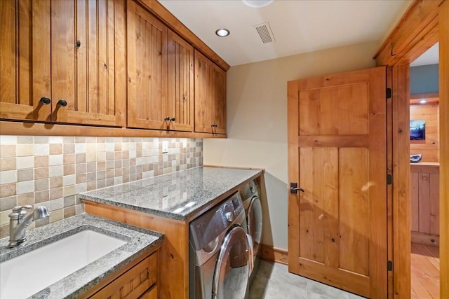 laundry room with cabinets, light tile patterned floors, washing machine and clothes dryer, and sink