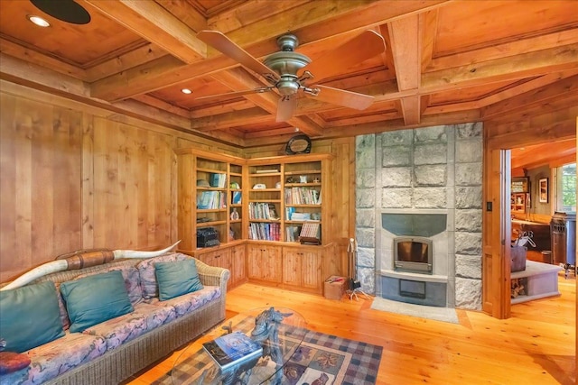 living room featuring hardwood / wood-style floors, beamed ceiling, a fireplace, wood walls, and coffered ceiling