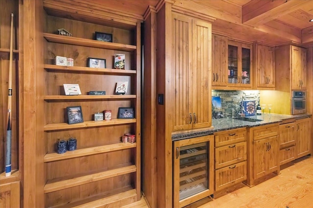 bar featuring light hardwood / wood-style floors, wooden ceiling, dark stone countertops, beverage cooler, and oven