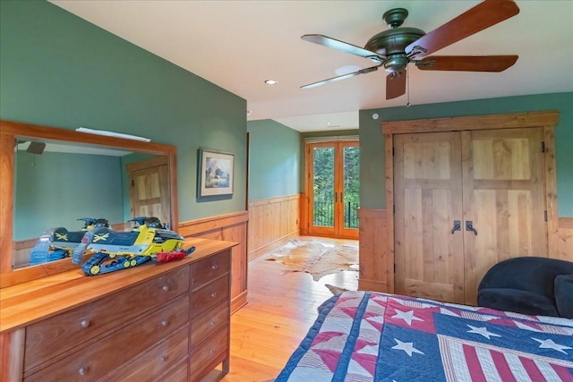 bedroom with ceiling fan, light hardwood / wood-style floors, and wooden walls