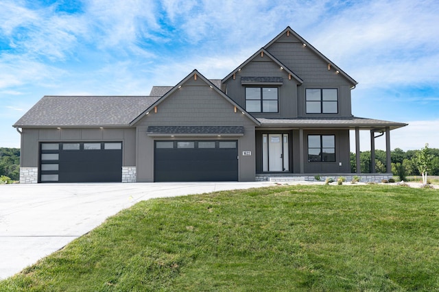 view of front of property with driveway, a shingled roof, a garage, and a front yard