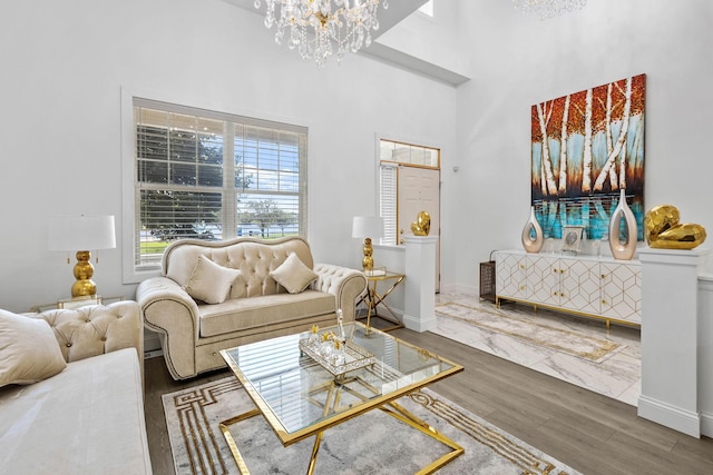 living room with hardwood / wood-style floors, a towering ceiling, and an inviting chandelier