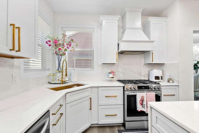 kitchen featuring white cabinets, custom range hood, sink, and appliances with stainless steel finishes