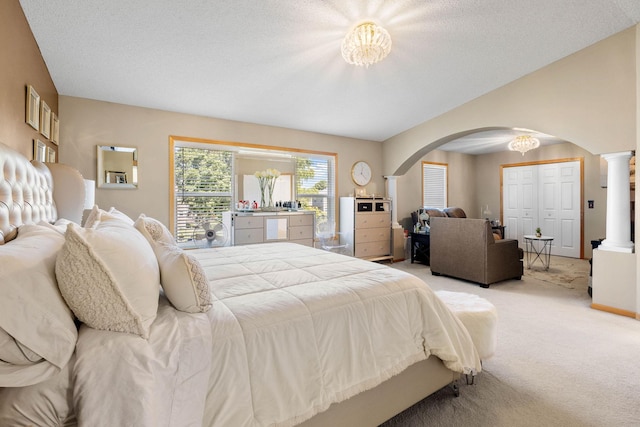 bedroom featuring a notable chandelier, decorative columns, light colored carpet, a textured ceiling, and a closet