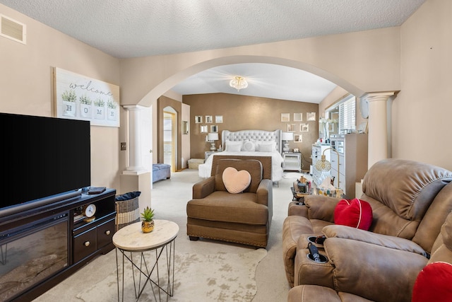 bedroom with a textured ceiling, lofted ceiling, light carpet, and decorative columns