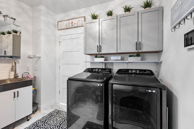 laundry area with washing machine and clothes dryer, sink, light tile patterned floors, and cabinets