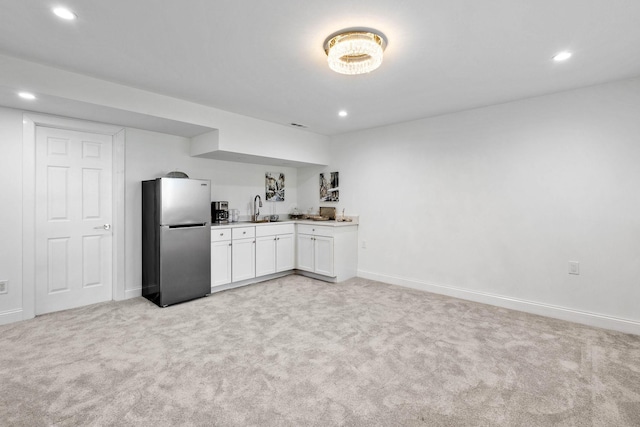 kitchen featuring stainless steel fridge, sink, white cabinets, and light colored carpet