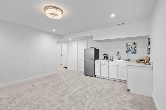 kitchen featuring white cabinetry, stainless steel fridge, sink, and light colored carpet