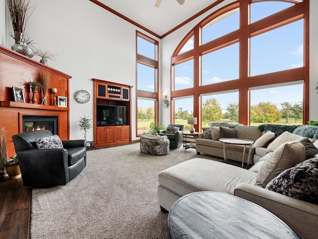 1599 Donway Ct NE, Alexandria, MN 56308 - carpeted living room with a high ceiling, crown molding, a glass covered fireplace, and ceiling fan