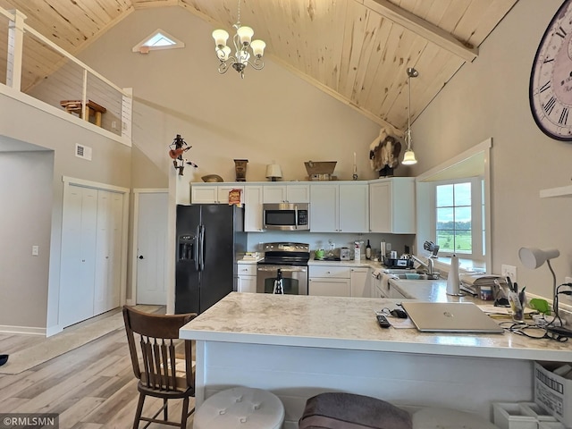 kitchen with white cabinets, appliances with stainless steel finishes, light countertops, and decorative light fixtures